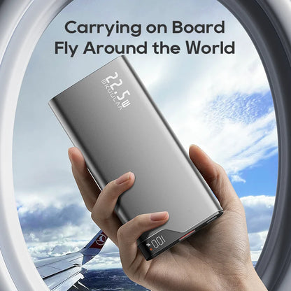 Hand holding a power bank with airplane window and clouds in the background