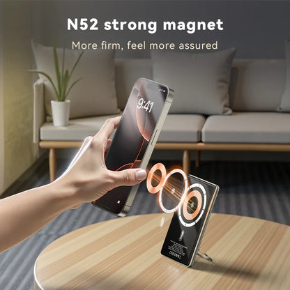 Smartphone being held above a charging stand with 'N52 strong magnet' text in a living room setting.